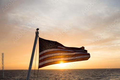 In waters near Isla Coiba National Park, the sun rises and illuminates an American flag that flies from an expedition cruise ship.; Isla Coiba National Park, Panama