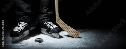 ice hockey. closeup of player skates with stick and puck on black background. banner with copy space