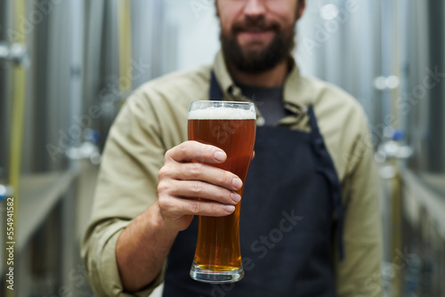 Cropped image of microbrewery owner holding big glass of beer photo