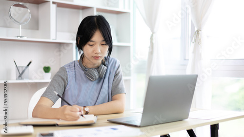 Asian woman taking notes in notebook while studying online in laptop at home, Video chat, Online communication , Stay home, New normal, Distance learning.., Social distancing, Learn online...