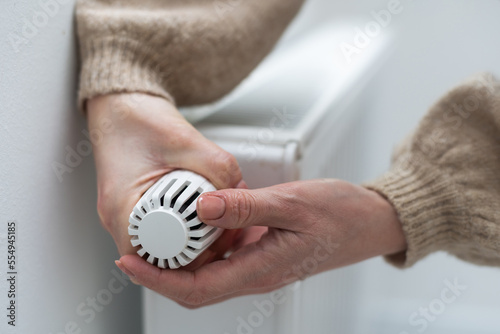 Fototapeta Naklejka Na Ścianę i Meble -  Woman holding temperature knob of heating radiator