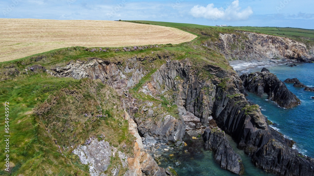 Farm fields on the shore of the Celtic Sea, south of Ireland, County Cork. Beautiful coastal area. Turquoise waters of the Atlantic. Picturesque stone hills. View from above.