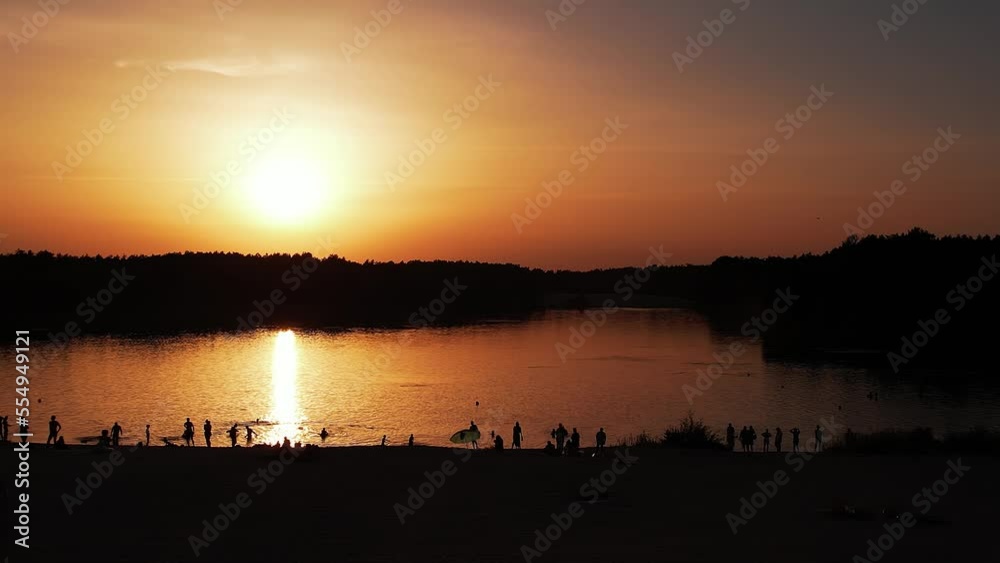 Shooting from quadcopter of beach with white sand and people who are sunbathing and swimming in the river at sunset