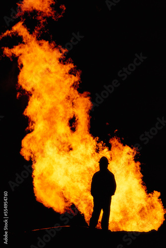 Oil field worker watches a flare at a natural gas drilling site; Pinedale, Wyoming, United States of America photo