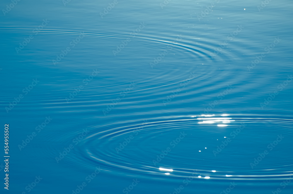 Wave ripple circles on the lake. Blurred transparent blue colored clear calm water surface texture. Trendy abstract nature background with copy space