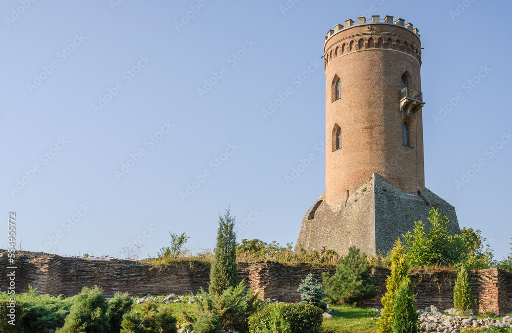 Medieval old brick tower of castle. Medieval building. Tower of ancient castle with opened windows. Historic architectural element on blue sky background