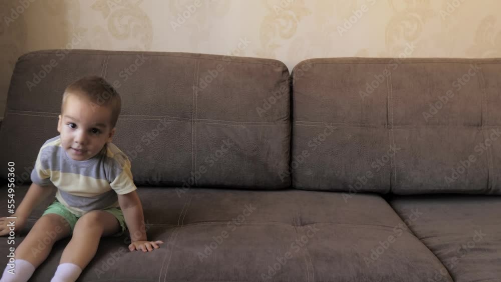 Cute little2 years old caucasian boy is jumping on the sofa, in the living room, active kid jump and having fun in bedroom at home. Weekend playtime concept Cute little2 years old caucasian boy is jumping on the sofa, in the living room, active kid jump and having fun in bedroom at home. Weekend playtime concept