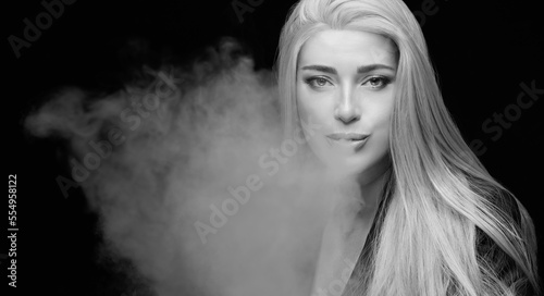 Fototapeta Naklejka Na Ścianę i Meble -  Beautiful sexy woman blowing smoke. Monochrome studio portrait isolated on black