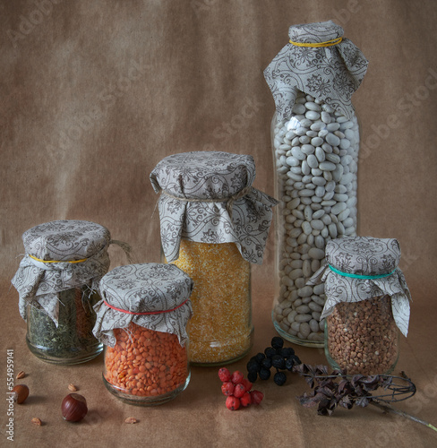A set of glass containers filled with different cereals. Nuts and dried berries on the table. Stocks of products