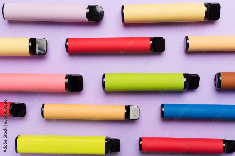 Disposable electronic cigarettes on color background, top view