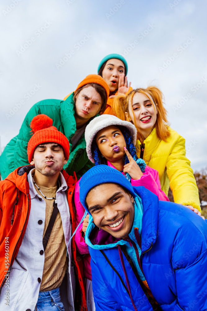 Multiracial group of young happy friends wearing colorful winter jackets meeting outdoors in winter, concepts about youth generation, millennials, teenage and students social gathering