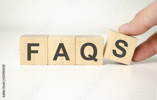 Businessman puts wooden blocks with the word FAQ frequently asked questions