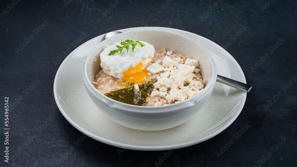 English breakfast oatmeal porridge with poached egg, goat cheese and pesto sauce. English breakfast oatmeal porridge with poached egg, goat cheese and pesto sauce.