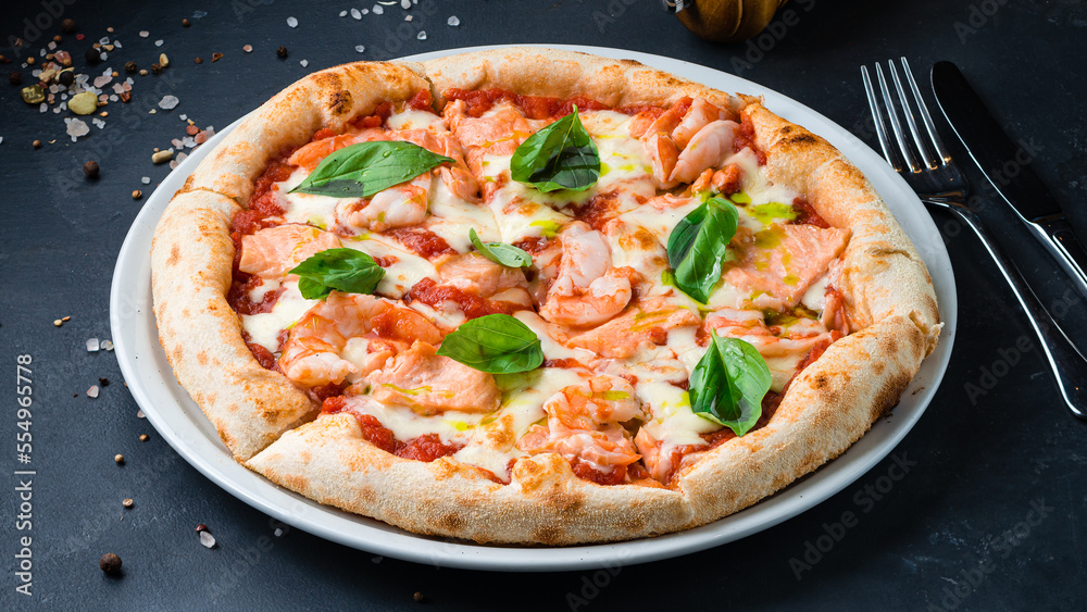 Italian pizza with shrimp, salmon, mozzarella, tomato sauce, basil on a thick dough with spices. Italian pizza with shrimp, salmon, mozzarella, tomato sauce, basil on a thick dough with spices.