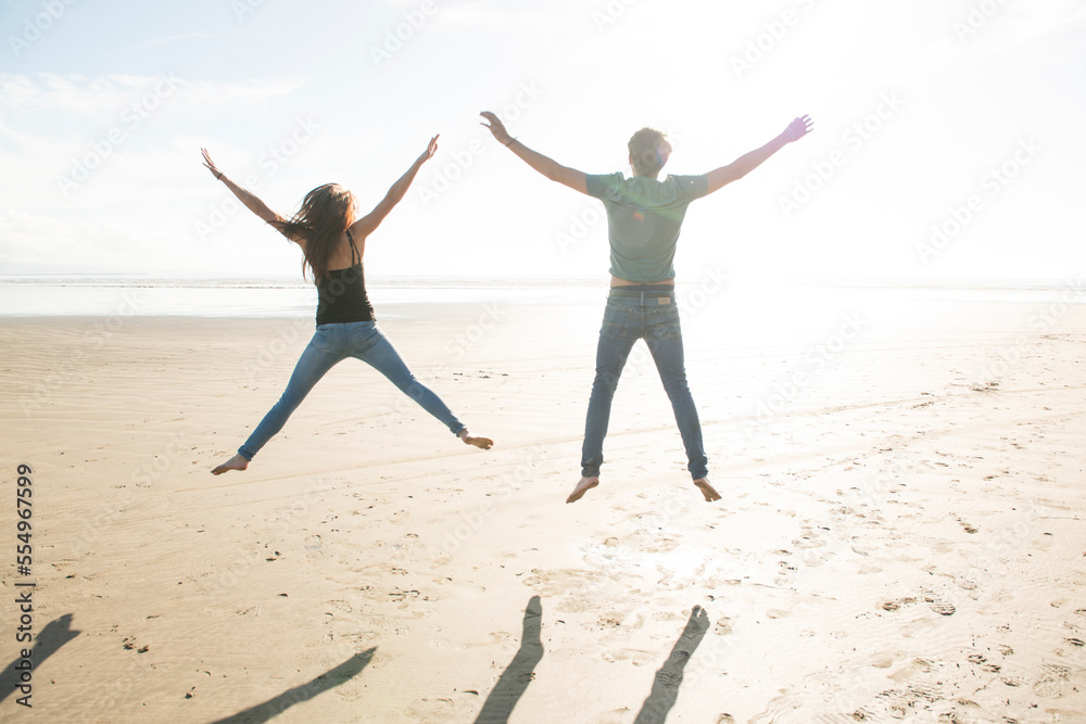 A young couple jumping in the sunshine on the beach at Porthmadog. A young couple jumping in the sunshine on the beach at Porthmadog.
