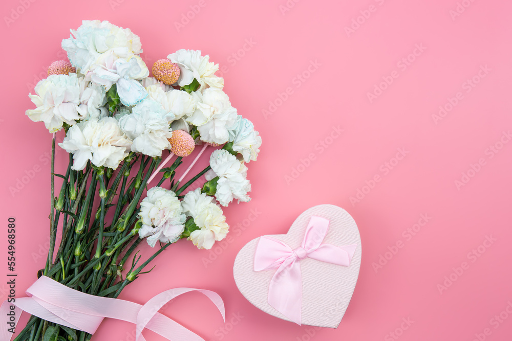 Bouquet of flowers, heart shaped gift box on pink background, flat lay.