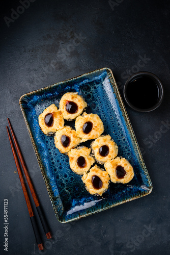 Hot sushi rolls with salmon, cream cheese, avocado, baked cheese and teriyaki sauce.