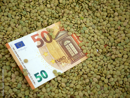there are dried green lentils and 50 euro bills in a container, lentil prices, pulses and food crisis,