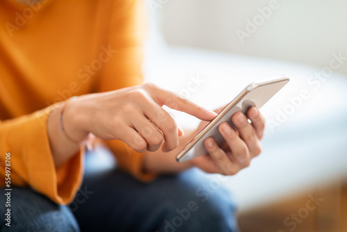 Unrecognizable Woman Using Modern Smartphone While Sitting On Couch At Home