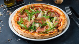 Italian cuisine pizza with ham, parmesan, tomato sauce, arugula and spices.