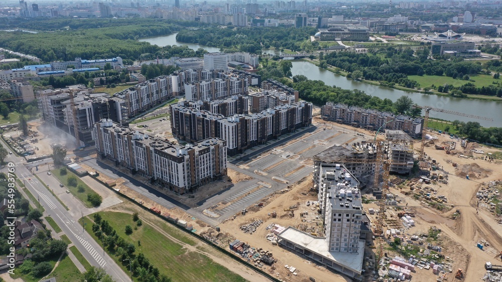 Construction of a residential microdistrict in the center of Minsk on the banks of the Svisloch River. The architecture of multi-storey residential buildings in Eastern Europe. High-rise cranes.