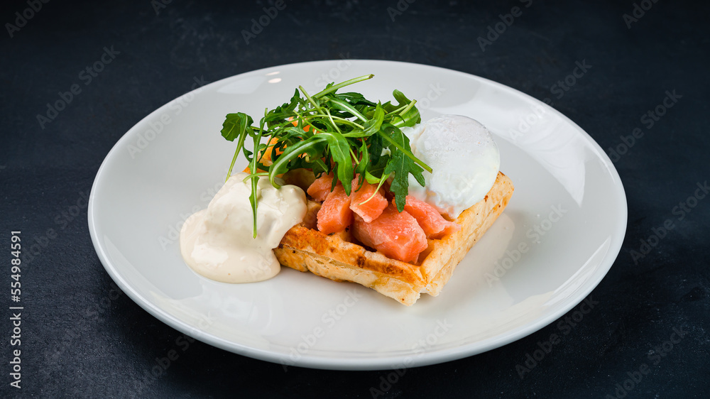 Viennese waffles with salmon fish, poached egg, arugula and sauce. Viennese waffles with salmon fish, poached egg, arugula and sauce.