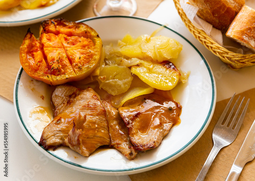Appetizing pork in sauce with baked potatoes and grilled tomato