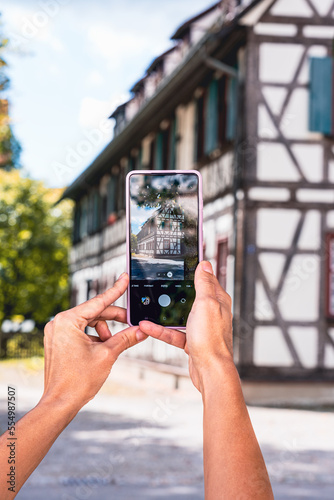 phone in the hands of a girl photographing an old house