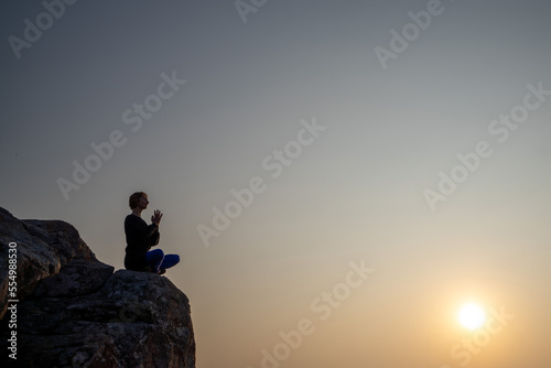 Yogini watching a sunrise, sunset on a tranquil Indian Tibet Nepal mountain. Namaste. Sun Salutation.