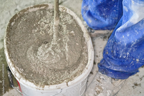 Mortar cement paste, mostly dry, mixed in bucket at house construction site, closeup detail from above