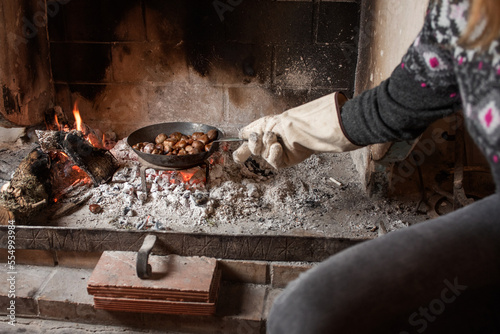 Obraz na plátně Detail of a woman's arm holding a frying pan with grilled chestnuts, uncooked go