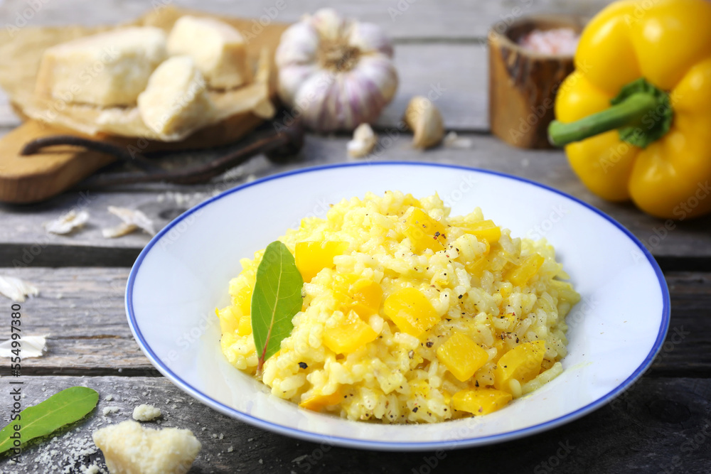 Italian food. Plate of yellow bell pepper risotto and grated parmesan cheese