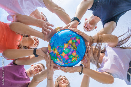 The concept of saving the world. A group of friends hold the world globe in their hands.