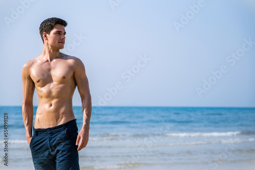 Portrait of handsome sexy caucasian man on the beach. Young healthy skin sun tan male with slim fit body. Beauty happy guy relax enjoy holiday travel vacation. 20s fitness caucasian man at the beach. © paulaphoto