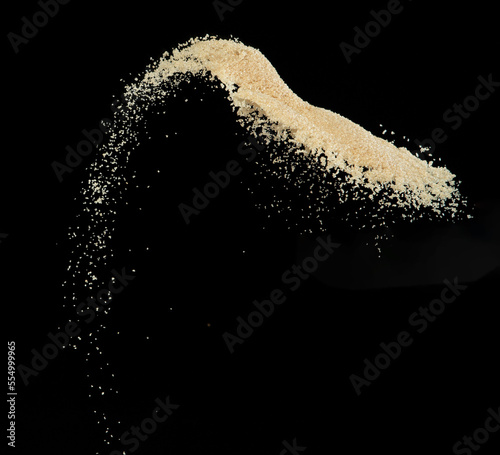 Brown Sugar flying explosion, brown grain sugar explode abstract cloud fly. Beautiful complete seed sugarcane splash in air, food object design. Selective focus freeze shot Black background isolated