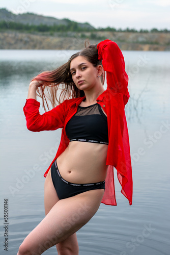 a girl in a black swimsuit and a red shirt in the lake