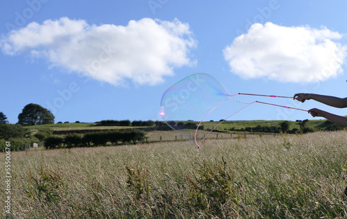Giant Soap Bubble with a Bubble wand in field in summer
