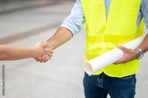 Two engineers shaking hands with deals and success agreements at the construction site. Architect and worker handshaking on construction site.