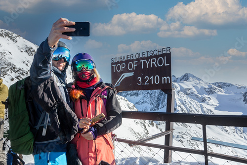 Happy skier and snowboarder couple taking a selfie photo on top of Tyrol, Austria photo