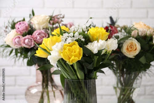 Beautiful bouquets with fresh flowers against white brick wall  closeup