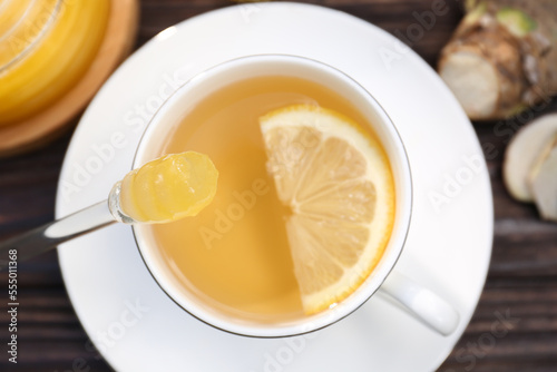 Cup of delicious tea with lemon and honey on wooden table, top view