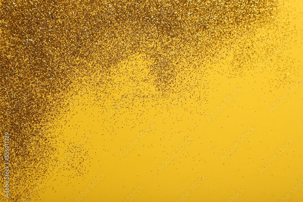 Shiny golden glitter on yellow background, top view. Space for text