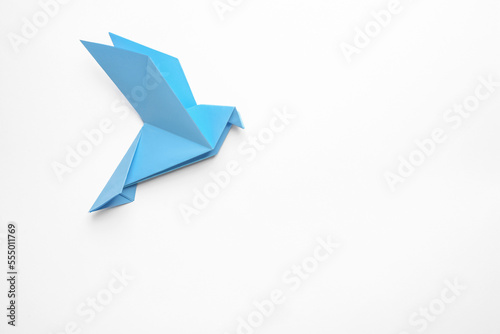 Beautiful light blue origami bird on white background, top view. Space for text