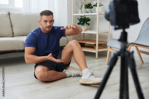 Man athlete blogger records exercise training on the body at home on camera, sports blogger bodybuilder, the concept of health and beauty