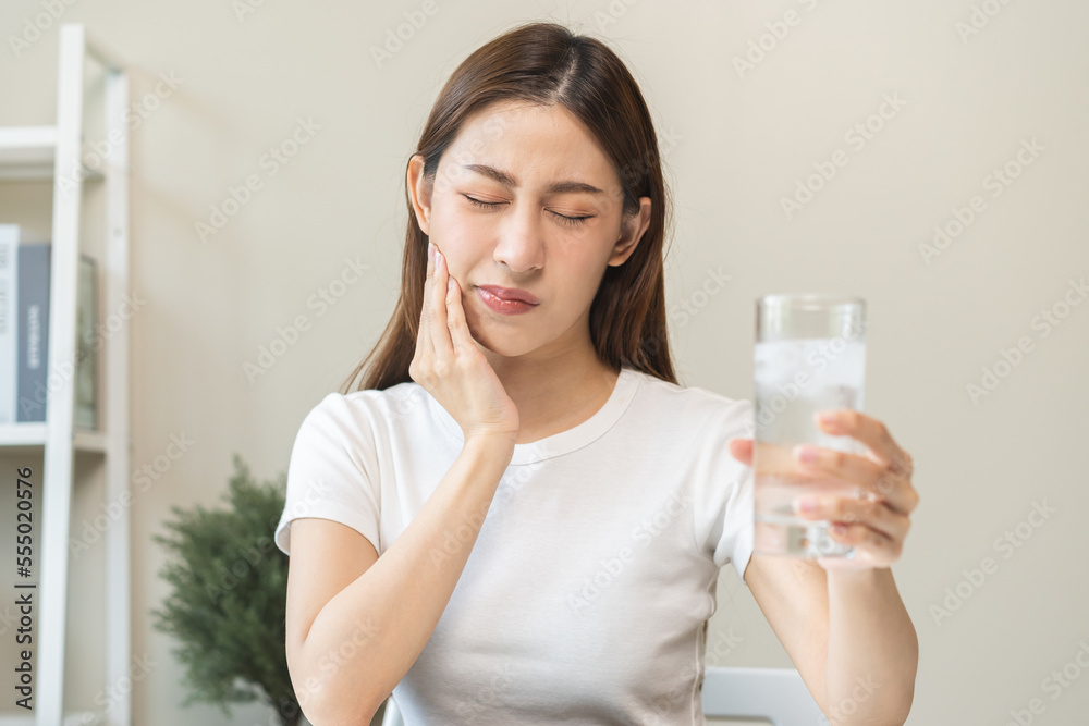 Suffering from toothache, asian young woman, girl touch cheek, face expression ache or feel pain, sensitive molar teeth, hand holding glass of water with ice, inflammation when drink cold, healthcare. Suffering from toothache, asian young woman, girl touch cheek, face expression ache or feel pain, sensitive molar teeth, hand holding glass of water with ice, inflammation when drink cold, healthcare.