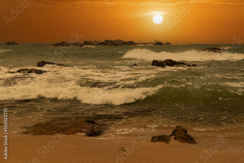 beautiful sunset over the ocean with rocks in the foreground