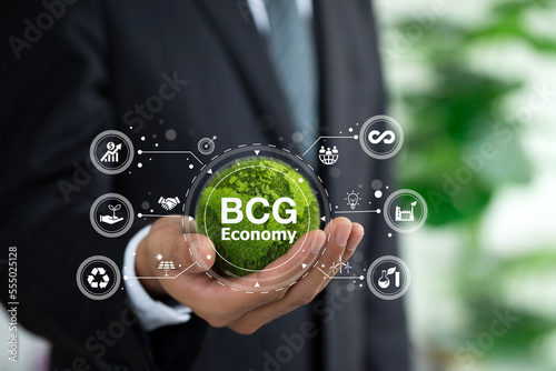 BCG concept for sustainable economy development. Bio economy, circle economy, green economy.Businessman holding the green world with BCG icons. New economic model for inclusive and sustainable growth. photo