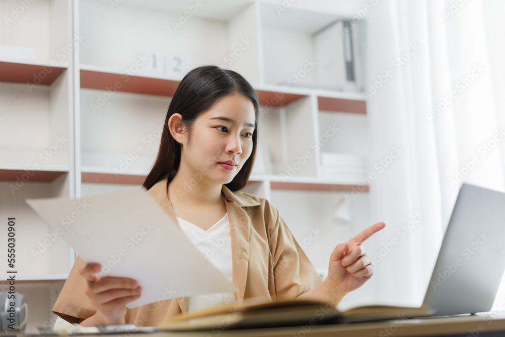 Online lifestyle concept A working woman checking for some information on the notebook which relates to the one on the paper. Online lifestyle concept A working woman checking for some information on the notebook which relates to the one on the paper.