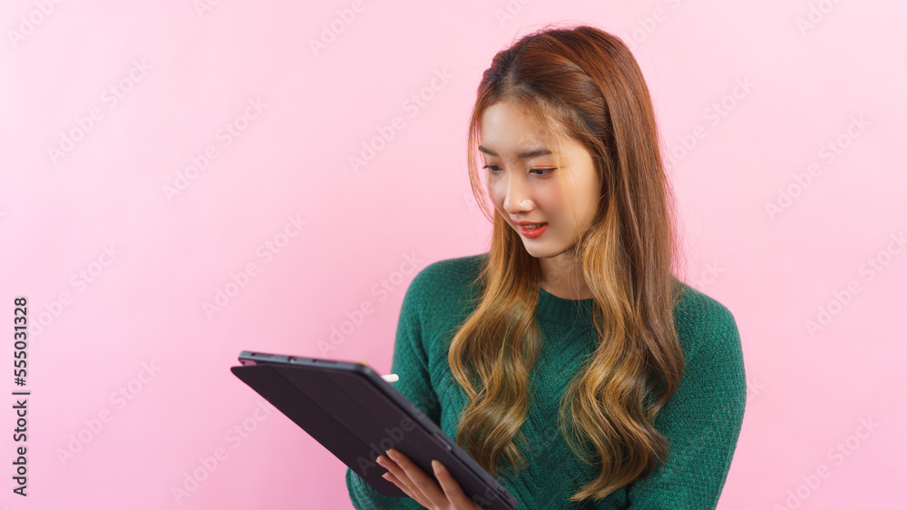 Businesswoman are working and writing business data in tablet isolated on pink background Businesswoman are working and writing business data in tablet isolated on pink background