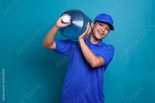 Asian delivery guy in blue uniform work as dealer courier carrying a water gallon